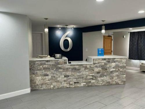 a lobby with a stone counter with a sign on the wall at Motel 6 Williamstown, WV in Williamstown