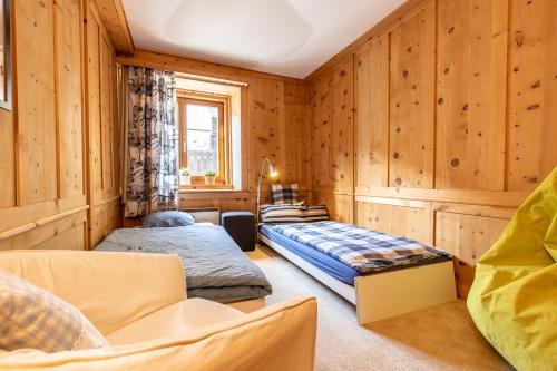 two beds in a room with wooden walls at Chasa Vi in Scuol