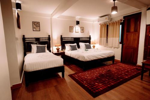a bedroom with two beds and a red rug at Ubon Huan Kaew อุบลเฮือนแก้ว in Ban Na Khwai