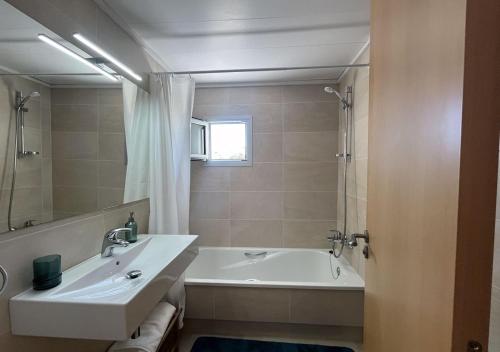 a bathroom with a tub and a sink and a mirror at 2-bedroom brand new apartment steps from the beach in Llança