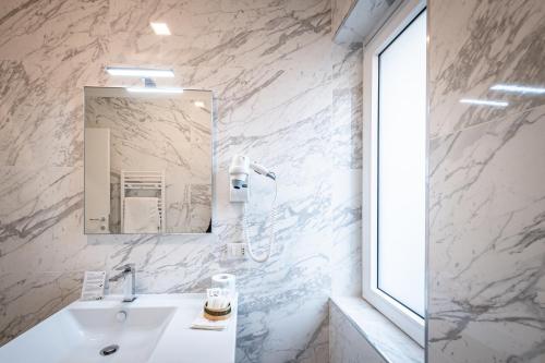 a white bathroom with a sink and a mirror at Hotel Cajeta in Buia