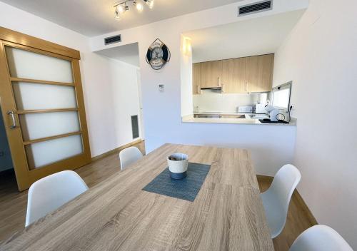 a dining room with a wooden table and white chairs at 2-bedroom brand new apartment steps from the beach in Llança