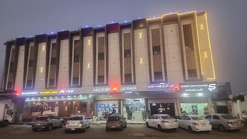 un edificio con coches estacionados frente a él en Loluat Al Matar Furnished Units en Jazan