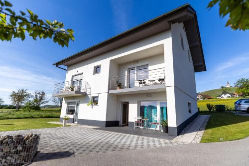 a white house with a balcony and a lawn at Apartments & Wellness Dalija with Massages studio in Podčetrtek