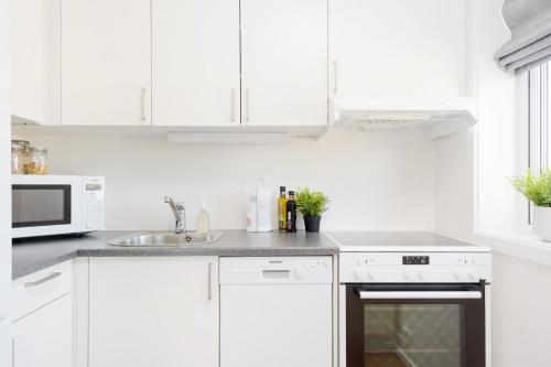 a white kitchen with white cabinets and a sink at The Apartments Company - Majorstuen in Oslo