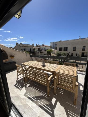 une table en bois et deux bancs sur une terrasse dans l'établissement Maison provençale (parking et vélos à disposition), au Grau-du-Roi