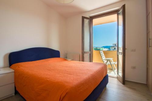 Olbia Oasis Apartment with Two Balconies! في أولبيا: غرفة نوم بسرير ولحاف برتقالي وشرفة