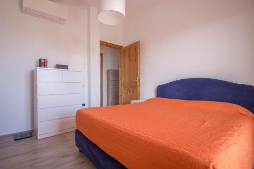 a bedroom with a bed with an orange blanket at Olbia Oasis Apartment with Two Balconies! in Olbia