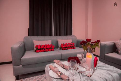 a living room with a gray couch with red roses at Loluat Al Matar Furnished Units in Jazan
