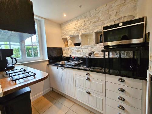 une cuisine avec un évier et un micro-ondes dans l'établissement Charmant Moulin - Jardin Secret - Vue sur l'Orne, à Culey-le-Patry