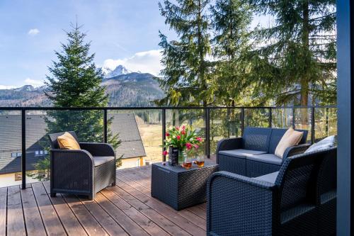 a patio with two chairs and a table on a deck at Apartament Widokowe Polany by Apart Concept Podhale in Kościelisko
