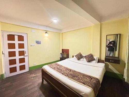 ein Schlafzimmer mit einem Bett und eine Person, die ein Foto macht in der Unterkunft HOTEL PURNI DARJEELING in Darjeeling