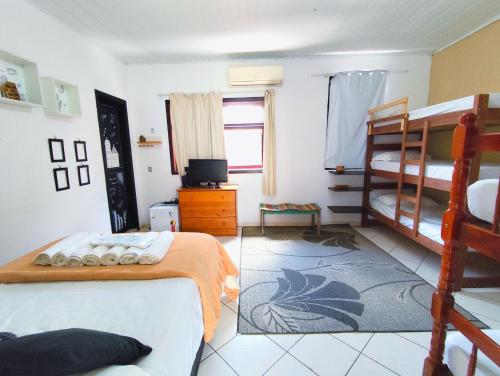 a bedroom with two bunk beds and a television at Pousada Lira Praieira Paraty in Paraty