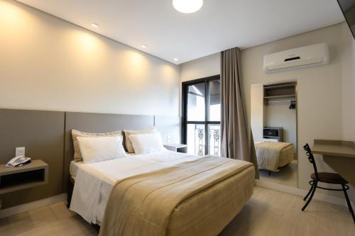 ein Hotelzimmer mit einem großen Bett und einem Schreibtisch in der Unterkunft Hotel Colonial in Itapetininga