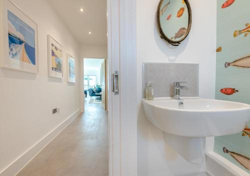 uma casa de banho com um lavatório e um espelho na parede em Sandy Toes - Dartmouth em Stoke Fleming