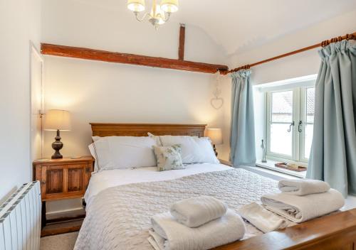 1 dormitorio con 1 cama grande y toallas. en White Rose Cottage, en Bodham