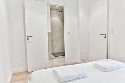 - une chambre blanche avec un lit et une douche dans l'établissement Appartement au centre de Paris - Musée Grévin, à Paris