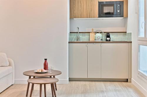 une petite cuisine avec une table et un micro-ondes dans l'établissement Appartement au centre de Paris - Musée Grévin, à Paris