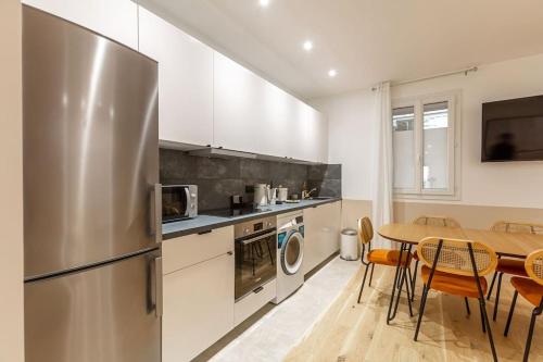 une cuisine avec une table et un réfrigérateur en acier inoxydable dans l'établissement Appart 6Pers#3 Bedrooms#2 Bathrooms#Paris 19, à Paris