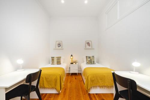 two beds in a room with white walls and wooden floors at Modern Nomad Hub Stylish Spaces for Remote Living in Lisbon