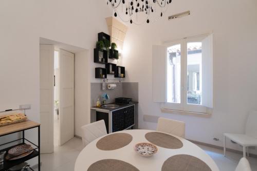 una sala da pranzo bianca con tavolo e sedie di Dimora Barocca Luxury Suites a Lecce