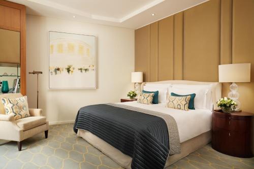 - une chambre avec un grand lit et une chaise dans l'établissement Corinthia London, à Londres