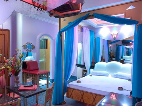 a bedroom with a large bed with blue curtains at Xangai Motel by Drops in São Leopoldo