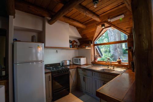 a kitchen with a white refrigerator and a window at Luna Roja Llao Llao in San Carlos de Bariloche