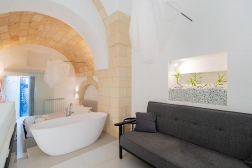 bagno con vasca bianca e lavandino di Dimora Barocca Luxury Suites a Lecce