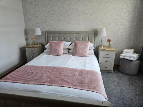 a bedroom with a large bed with pink pillows at 37 Farraline Court, City Centre apartment in Inverness