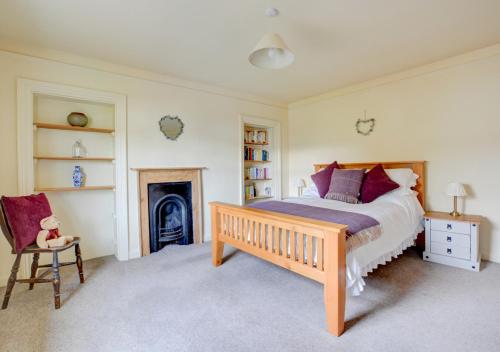 um quarto com uma cama, uma cadeira e uma lareira em Tusker House em Wells-next-the-Sea