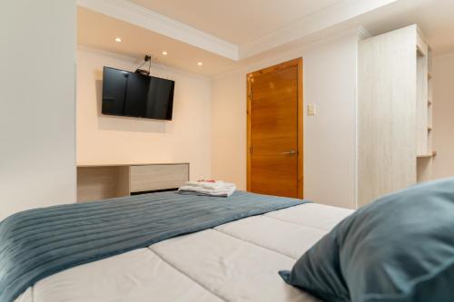 um quarto com uma cama e uma televisão na parede em Hotel Mareblu Iquique em Iquique