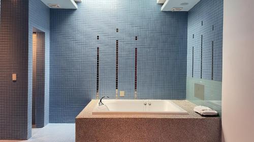 a bath tub in a bathroom with blue tiles at You Want Motel in Xizhi