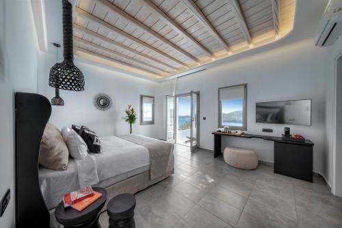 a bedroom with a bed and a desk and windows at Deliades Hotel in Ornos