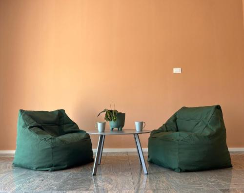 Dos sillas verdes y una mesa con una planta. en Martina’s Rooms, en Albignasego