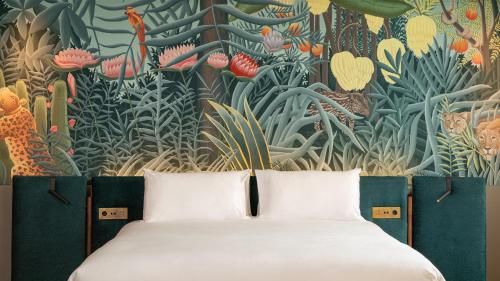 a bed in front of a mural of plants at Casa Faraona Luxury Residences in Madrid