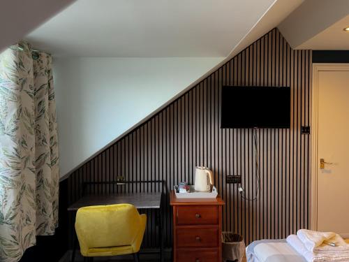 Habitación con cama y escritorio con silla amarilla. en Nomi Rooms & Restaurant en Bangor
