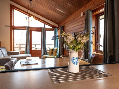 a vase with flowers on a table in a living room at Loch Insh Chalets Ltd in Kincraig