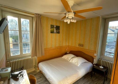 a bedroom with a bed with a ceiling fan at Hôtel de Verdun in Nevers