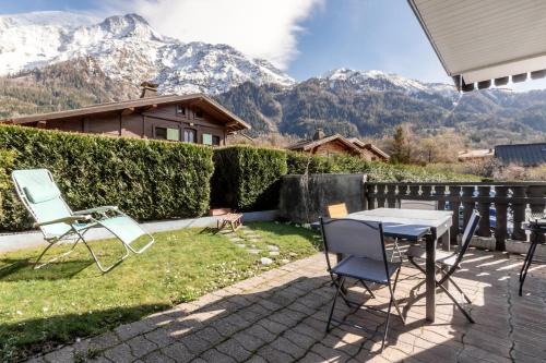 una mesa y sillas en un patio con montañas al fondo en Lilas - Awesome view of the Mont-Blanc Range, en Les Houches