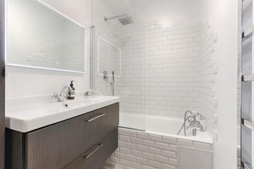 La salle de bains blanche est pourvue d'un lavabo et d'une baignoire. dans l'établissement Trocadero/TourEiffel : havre de paix 2 Chambres, à Paris