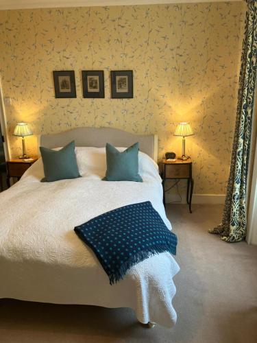 a bedroom with a large white bed with blue pillows at The Old Manse in Lowick