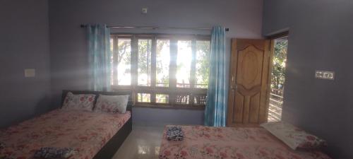 a bedroom with two beds and a window with a door at Nestle Beachfront Murudeshwar in Māvalli