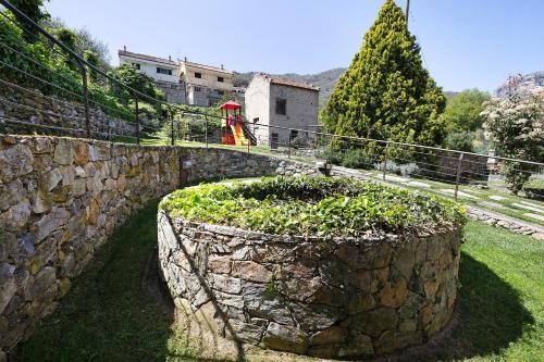 a stone wall with a plant in a garden at Melograno Agriturismo La Ferla in Toirano