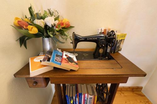 a table with a sewing machine and a vase of flowers at Melograno Agriturismo La Ferla in Toirano