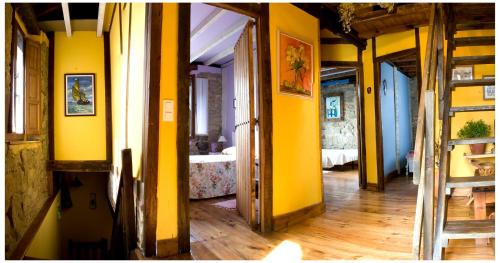 a hallway with yellow walls and a room with a bed at La casuca de Antoniooti in Las Rozas de Valdearroyo