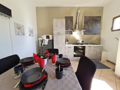 a kitchen with a table with black plates and red chairs at Appartamento Pederzoli in Peschiera del Garda