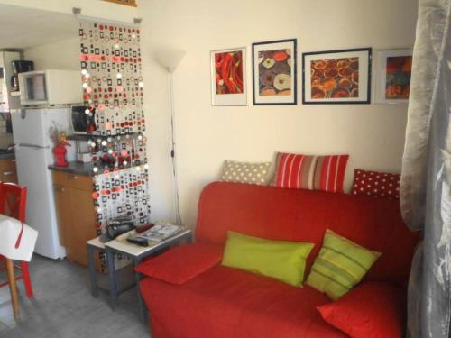 un salon avec un canapé rouge et une cuisine dans l'établissement MAS DU SOLEIL Agréable villa mitoyenne 3 pièces Mt St Martin cap d'Agde, au Cap d'Agde