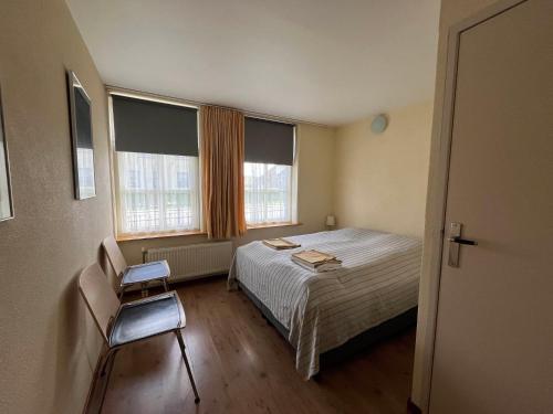 ein kleines Schlafzimmer mit einem Bett und zwei Fenstern in der Unterkunft It Winkelhûs in Terschelling