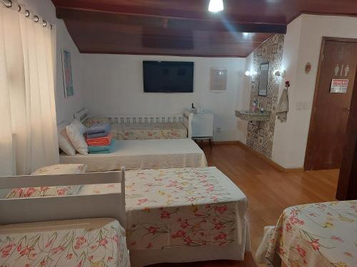 a room with three beds and a flat screen tv at Pousada Recanto da Fé in Cachoeira Paulista